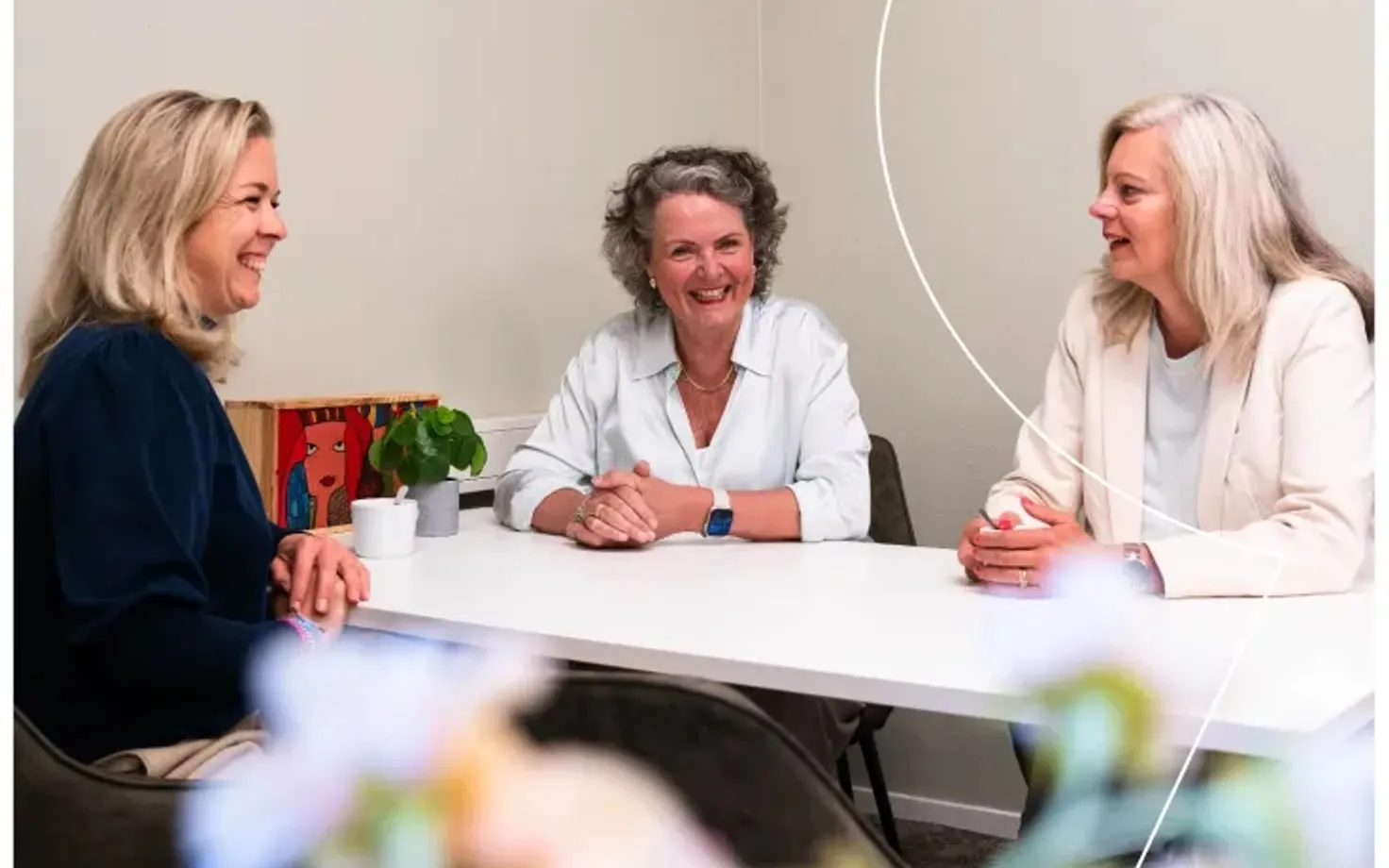 Drie vrouwen in overleg aan een tafel