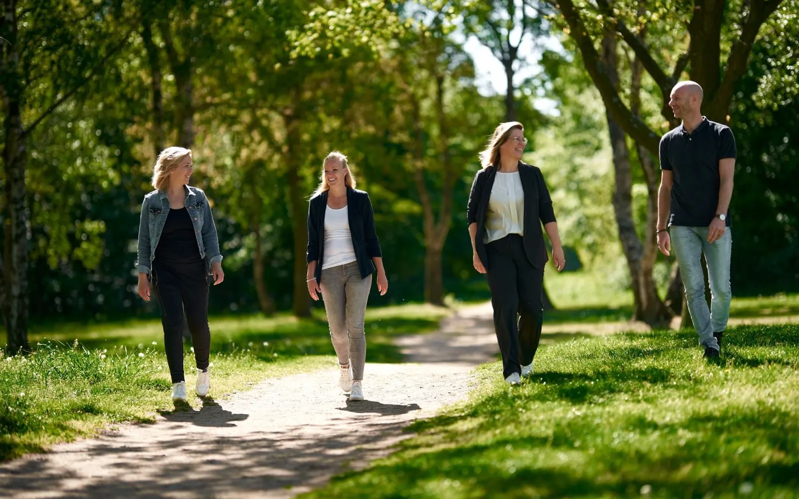 Vier collega's lopen in gesprek over een pad door het park