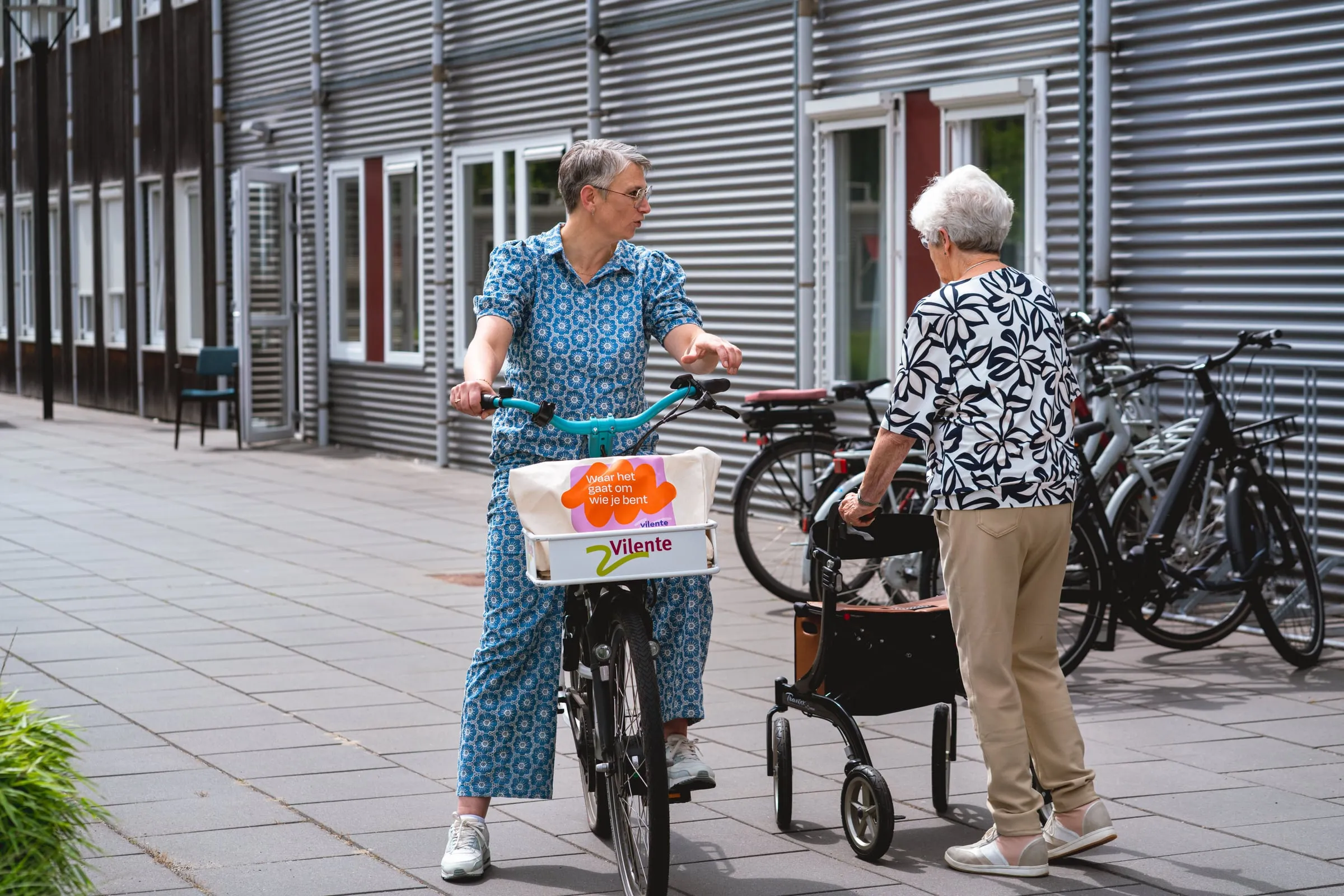 Een medewerker van Vilente in gesprek met een bewoner buiten bij de fietsenstalling